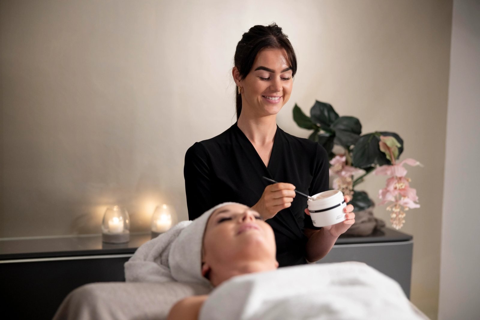 A practitioner performing a face treatment on her client